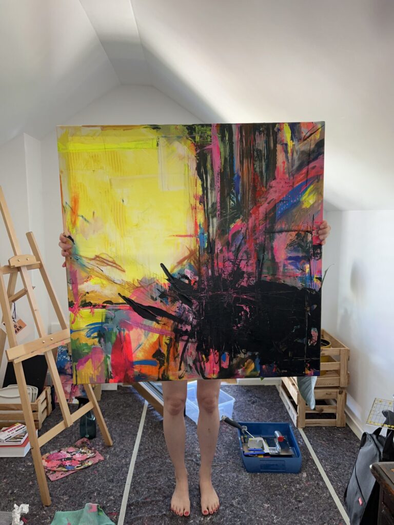 Das Kunstwerk im Raum: Originales abstraktes Gemälde in Neonfarben auf der Staffelei im hellen Atelier